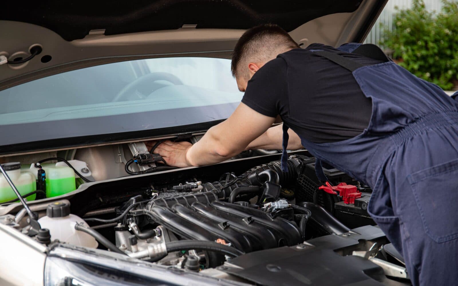 A technician inspecting an engine bay with the bonnet raised