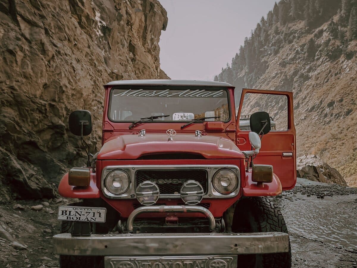 A red Japanese four-wheel-drive parked on a mountain track